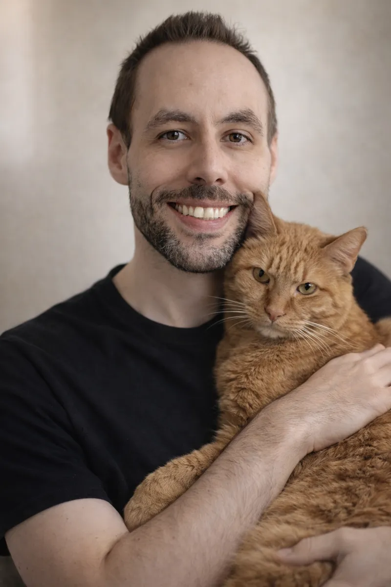 Patrick sitting with Meeko, his orange tabby cat, on the porch steps — the bond that inspired Rainbow Meadow